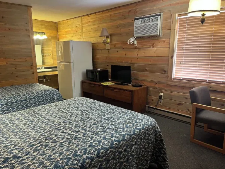 Deluxe Room with two beds in blue quilts, a full-size fridge, microwave and TV