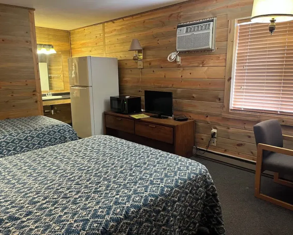 Deluxe Room with two beds in blue quilts, a full-size fridge, microwave and TV