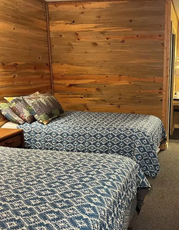 Deluxe Room beds against a knotty-pine wall